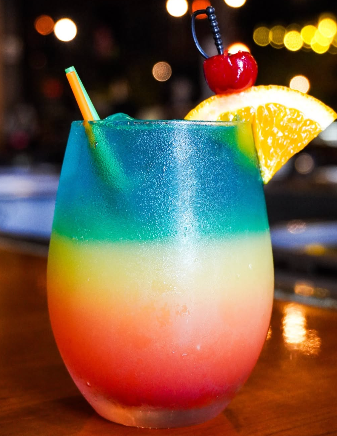 A colorful layered Volcano cocktail with citrus and a cherry