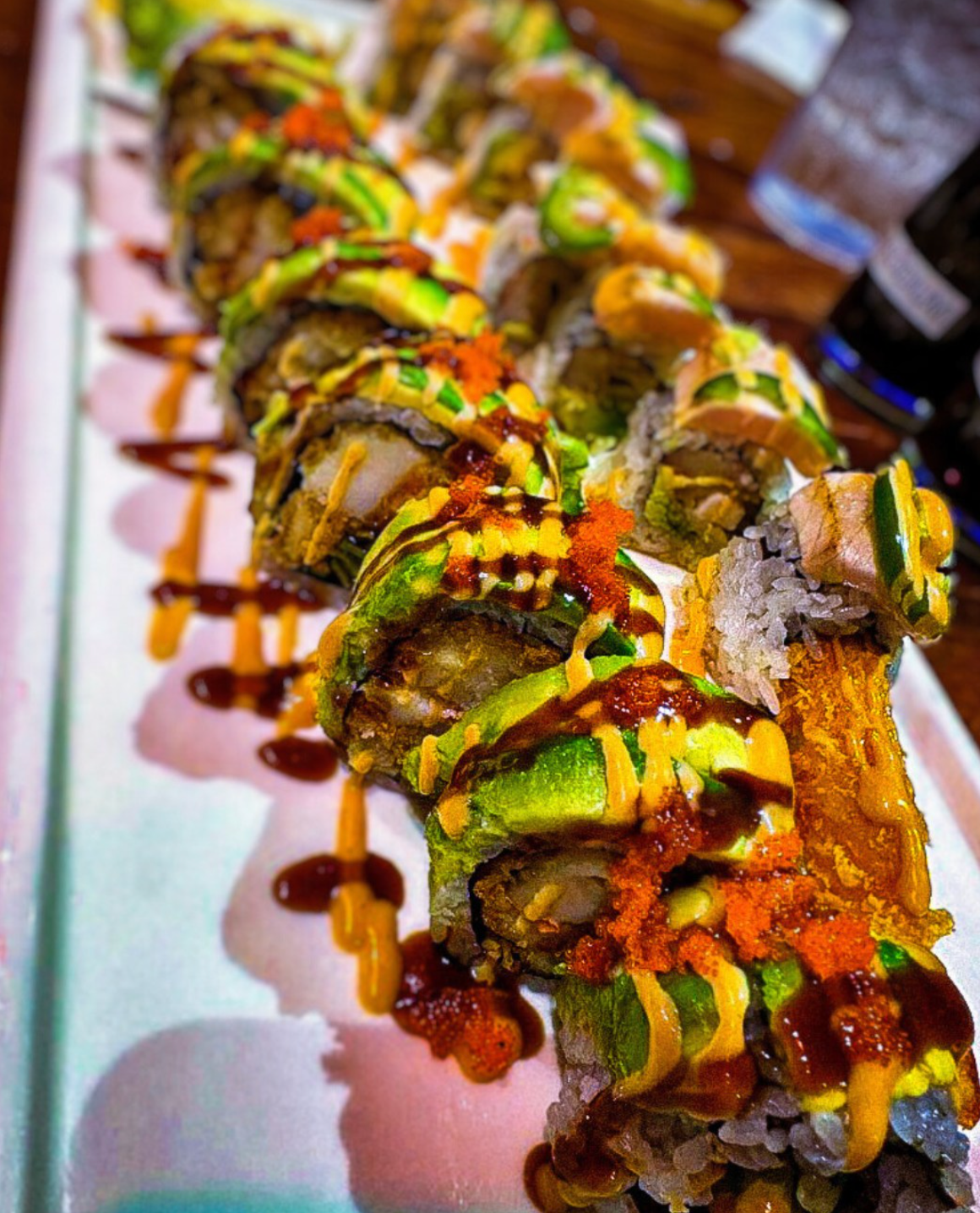 A close-up of Volcano sushi topped with sauce and fresh garnish
